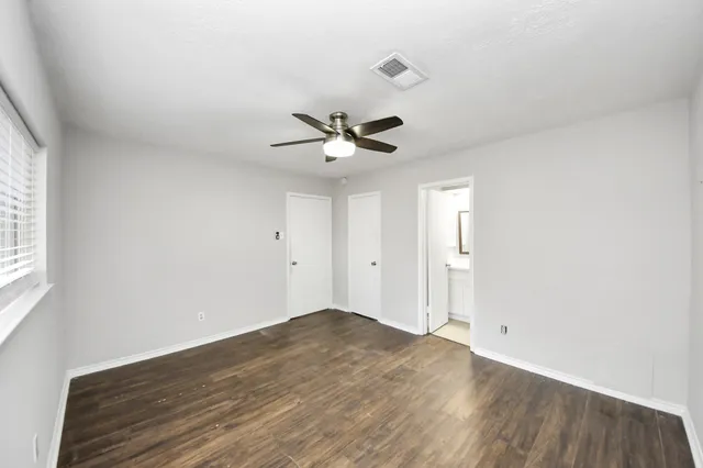 an empty room with a ceiling fan and window