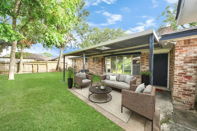 a view of a patio with couches potted plants and a big yard