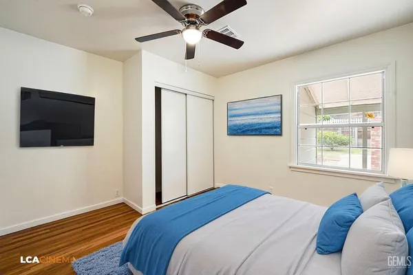 an empty room with wooden floor fan and windows