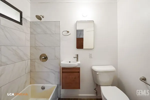 a bathroom with a toilet a sink a mirror and bathtub