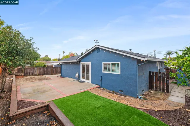 a backyard of a house with barbeque oven and trees