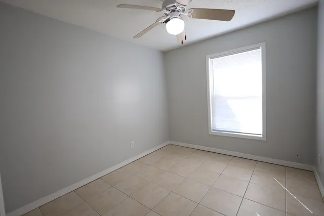 an empty room with a chandelier fan and windows