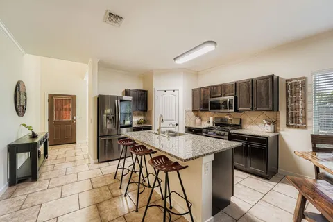 a kitchen with stainless steel appliances a stove a sink dishwasher a refrigerator a microwave oven with white cabinets and wooden floor