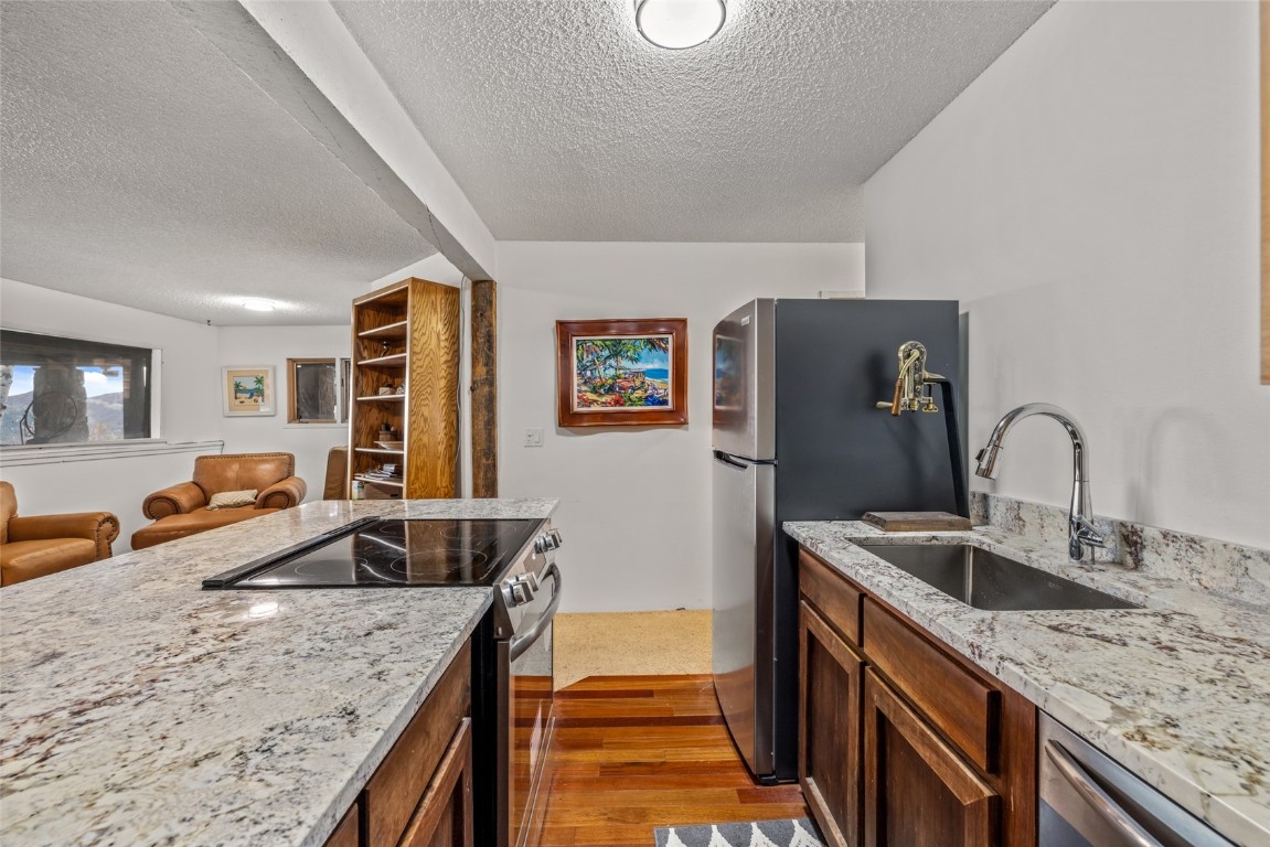 2350 Glacier Ridge Steamboat Springs, CO 80487 - Photo 35 of 47 a kitchen with granite countertop a sink and a refrigerator