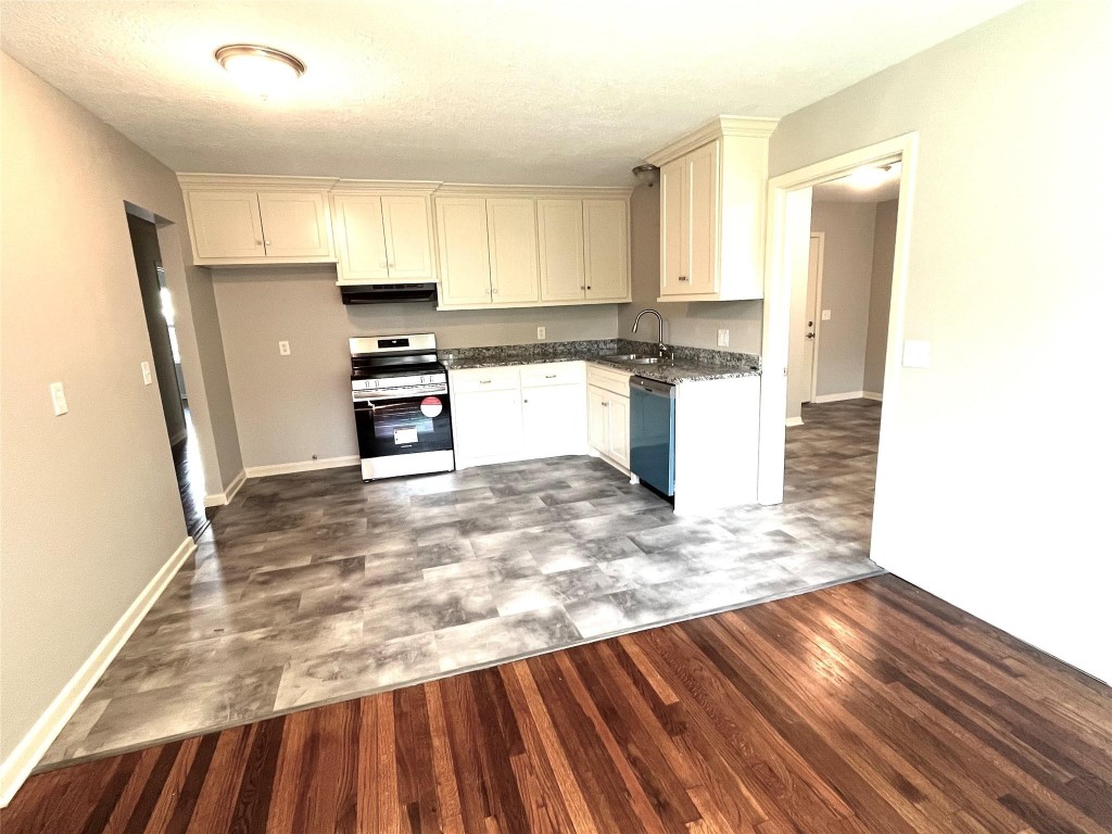 104 Peach Street Tomball, TX 77375 - Photo 6 of 19 a kitchen with granite countertop a refrigerator and a stove top oven