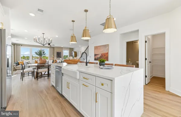 a kitchen with stainless steel appliances a dining table chairs a refrigerator and cabinets