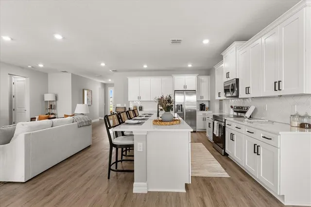 a large white kitchen with lots of counter top space a sink appliances and cabinets