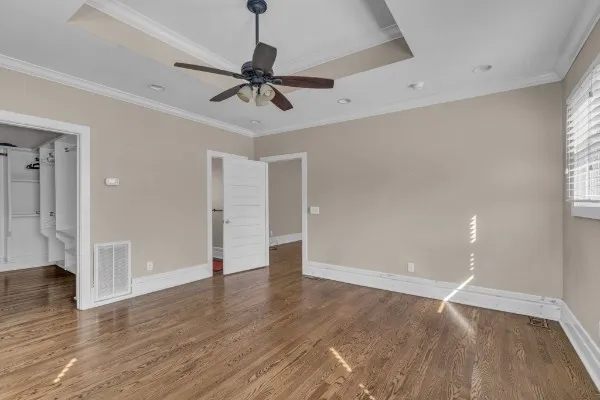 a view of an empty room with wooden floor and window