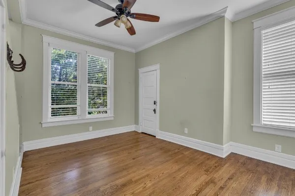a view of an empty room with wooden floor and a window