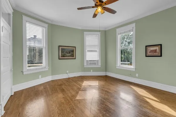 a view of empty room with wooden floor and fan