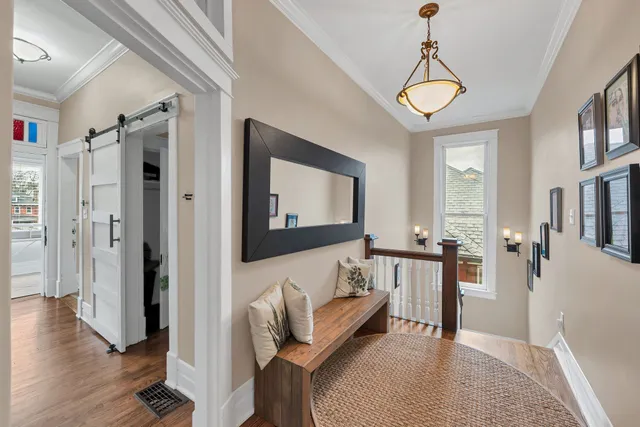 a view of a hallway to a livingroom with wooden floor and furniture