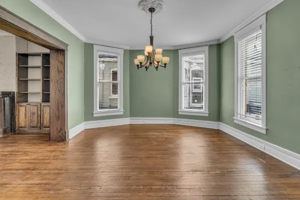 a view of an room with wooden floor chandeliers and kitchen view