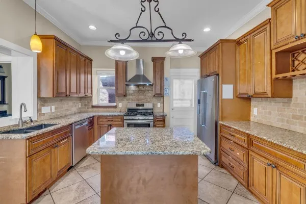 a kitchen with stainless steel appliances granite countertop a sink a stove top oven a refrigerator cabinets and wooden floor