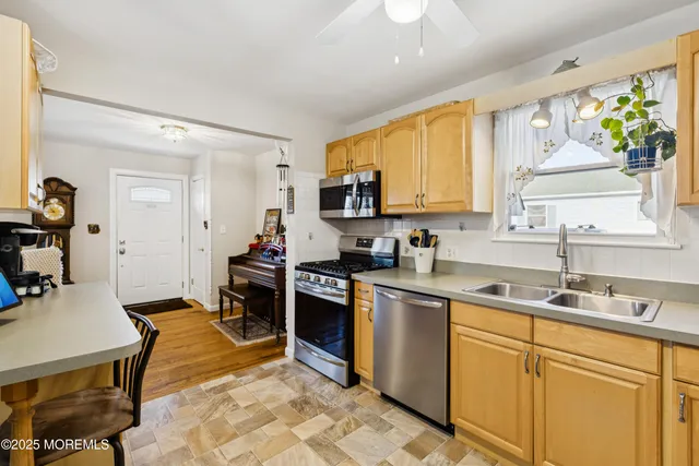 a kitchen with stainless steel appliances granite countertop a sink dishwasher a stove top oven a dining table and chairs with wooden floor