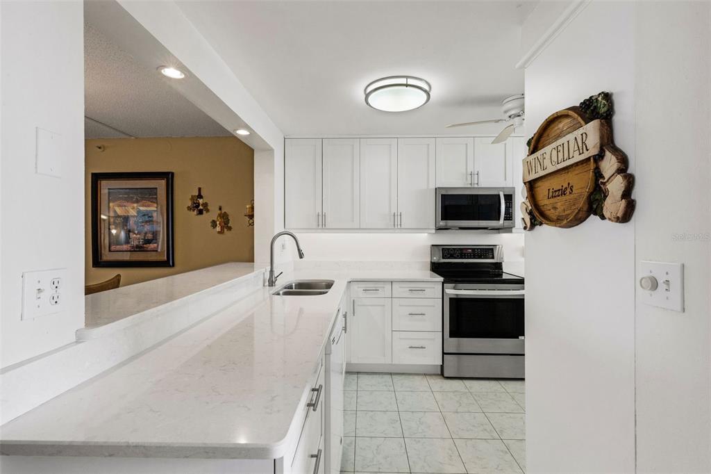 14900 Gulf Boulevard, Unit 410 Madeira Beach, FL 33708 - Photo 11 of 76 a kitchen with stainless steel appliances granite countertop a sink and a stove