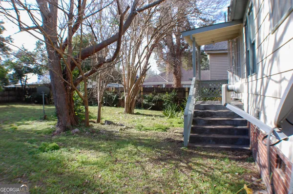 a backyard of a house with plants and large trees