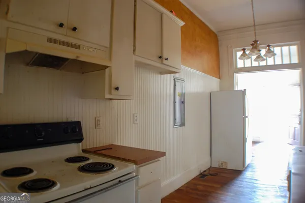 a kitchen with a stove and wooden floor