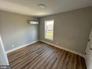a view of an empty room with wooden floor and closet