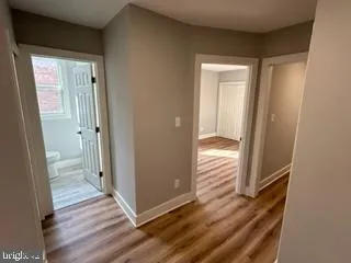 a view of a hallway with wooden floor and a living room