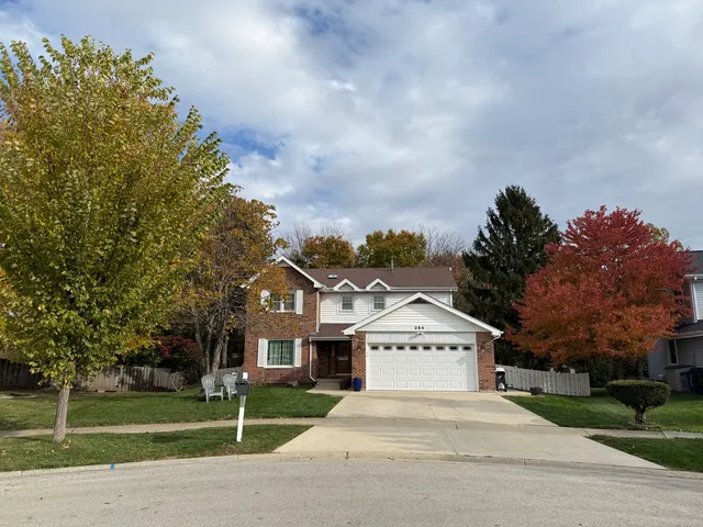 a front view of a house with a garden and trees