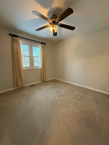 an empty room with windows and ceiling fan