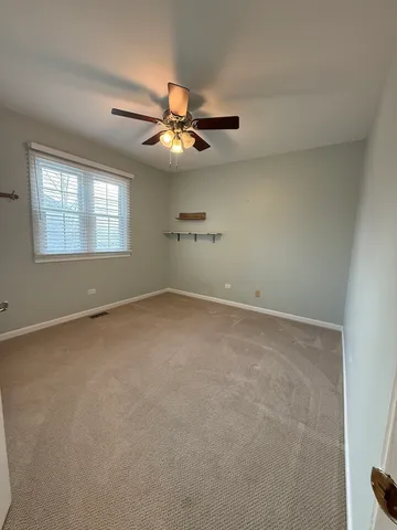 an empty room with windows and fan