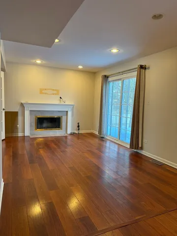 an empty room with wooden floor fireplace and windows