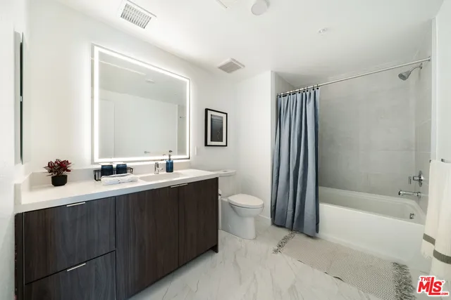 a bathroom with a double vanity sink toilet mirror and bathtub