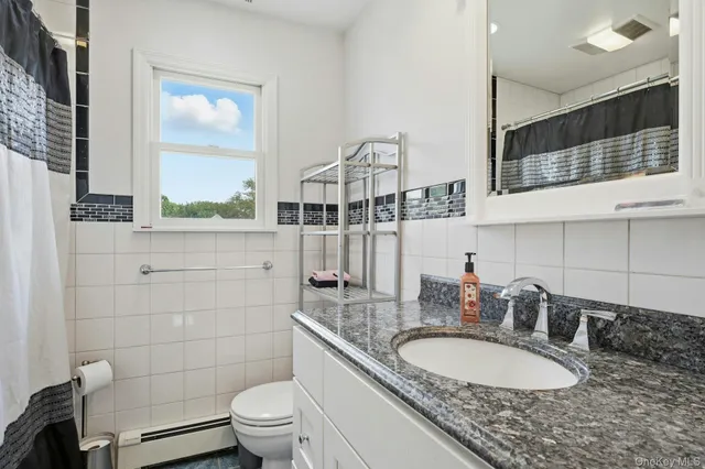 a bathroom with a granite countertop double vanity sink a mirror and a toilet