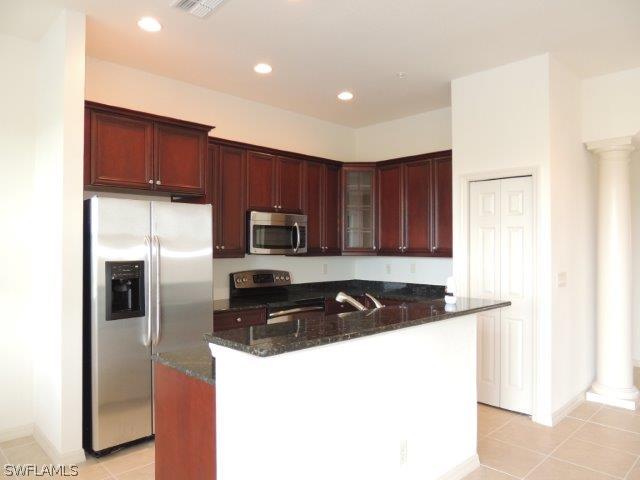 3590 Lansing Loop, Unit 201 Estero, FL 33928 - Photo 2 of 16 a kitchen with a refrigerator a stove a microwave and cabinets