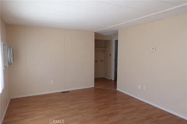 a view of an empty room with wooden floor and closet
