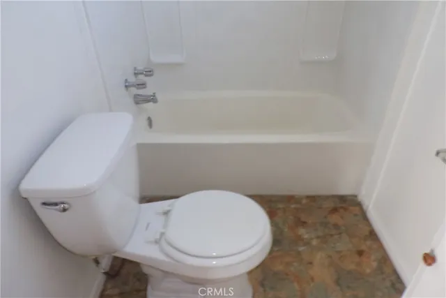 a white toilet sitting next to a bath tub