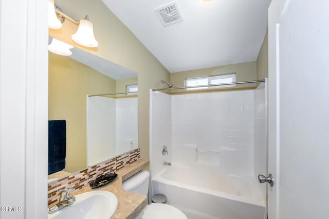 a bathroom with a bathtub shower sink vanity and a toilet