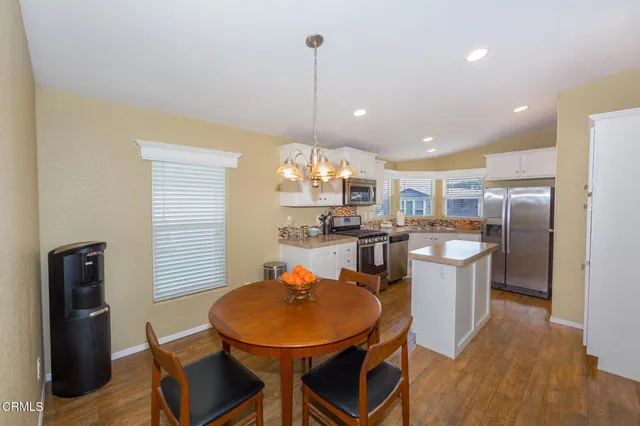 a kitchen with stainless steel appliances kitchen island granite countertop a table chairs and a refrigerator