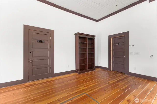 an empty room with wooden floor closet and windows