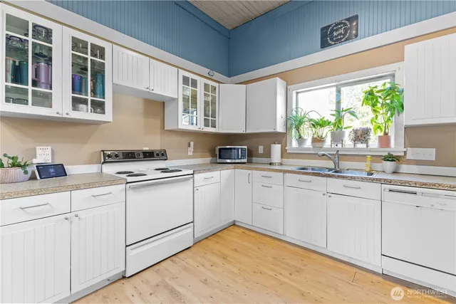 a kitchen with stainless steel appliances granite countertop white cabinets a sink and a large window