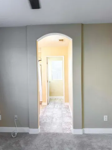 a view of a hallway with wooden floor and a bathroom