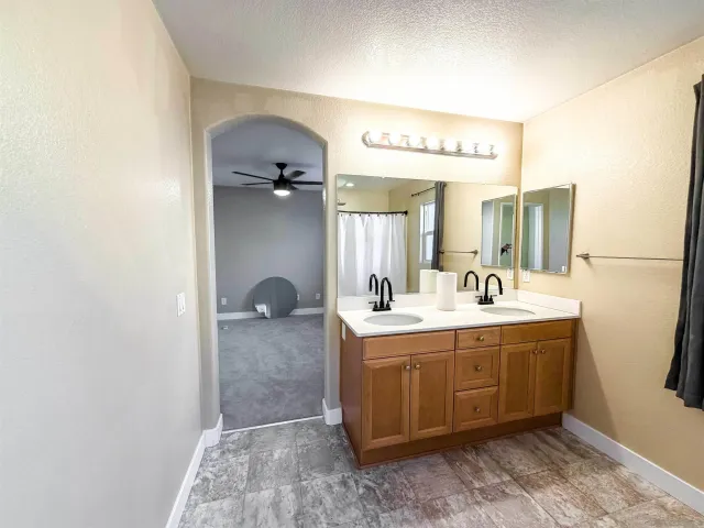 a en suite bathroom with a granite countertop sink and mirror
