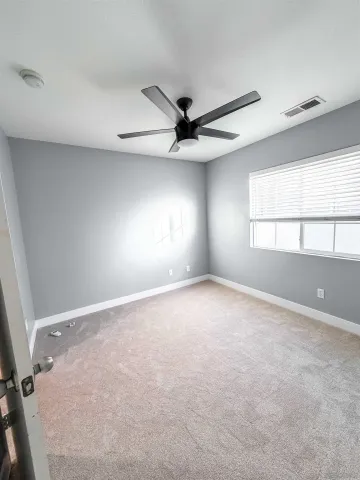 an empty room with windows and ceiling fan