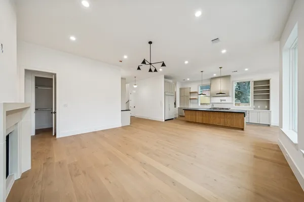 a kitchen with stainless steel appliances granite countertop a stove top oven a sink dishwasher and a fireplace with wooden floor