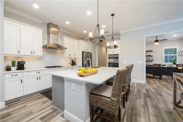 a kitchen with stainless steel appliances kitchen island granite countertop a table chairs and a refrigerator