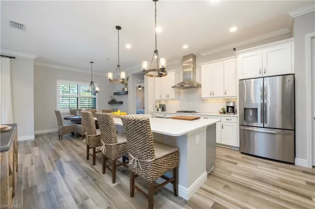 a kitchen with stainless steel appliances granite countertop a refrigerator a sink dishwasher a stove and white countertops with wooden floor