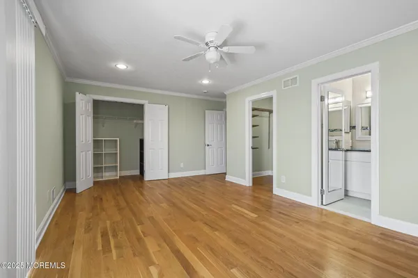 a view of an empty room with wooden floor and a ceiling fan