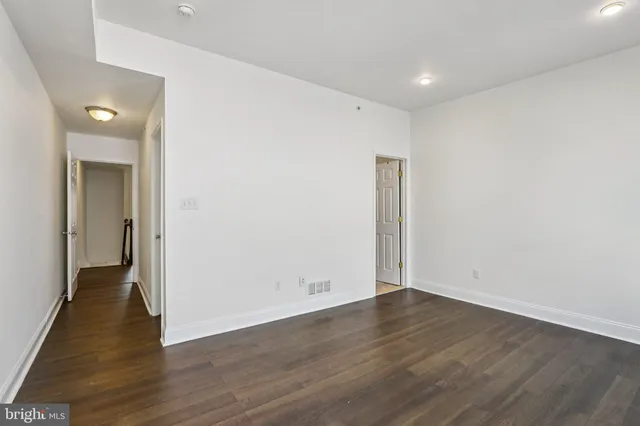 a view of an empty room with wooden floor and closet