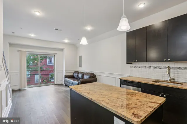 a living room with stainless steel appliances kitchen island granite countertop furniture and a flat screen tv