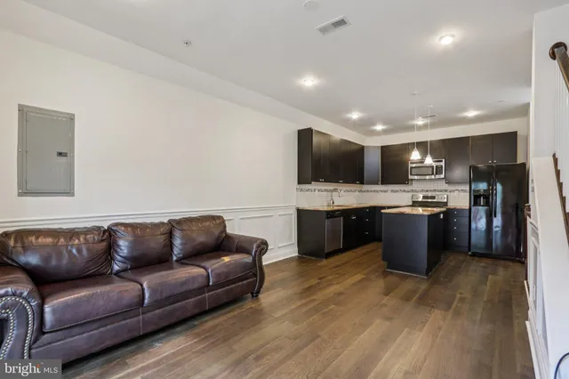 a living room with stainless steel appliances furniture and a kitchen view