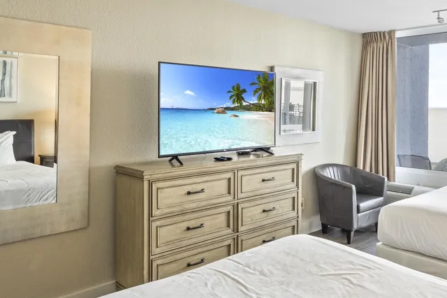 a bedroom with a bed and a flat tv screen on dresser