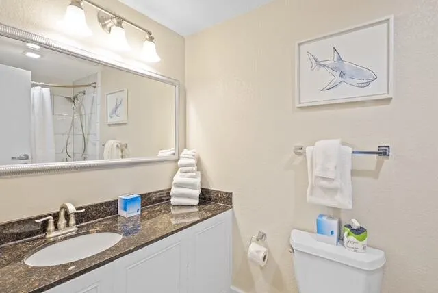 a bathroom with a granite countertop sink mirror vanity and toilet