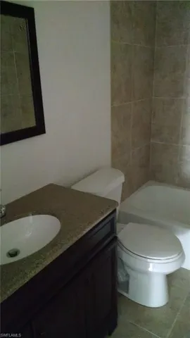 a bathroom with a granite countertop toilet and a sink