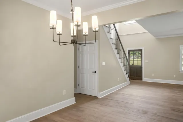 an empty room with wooden floor chandelier and windows